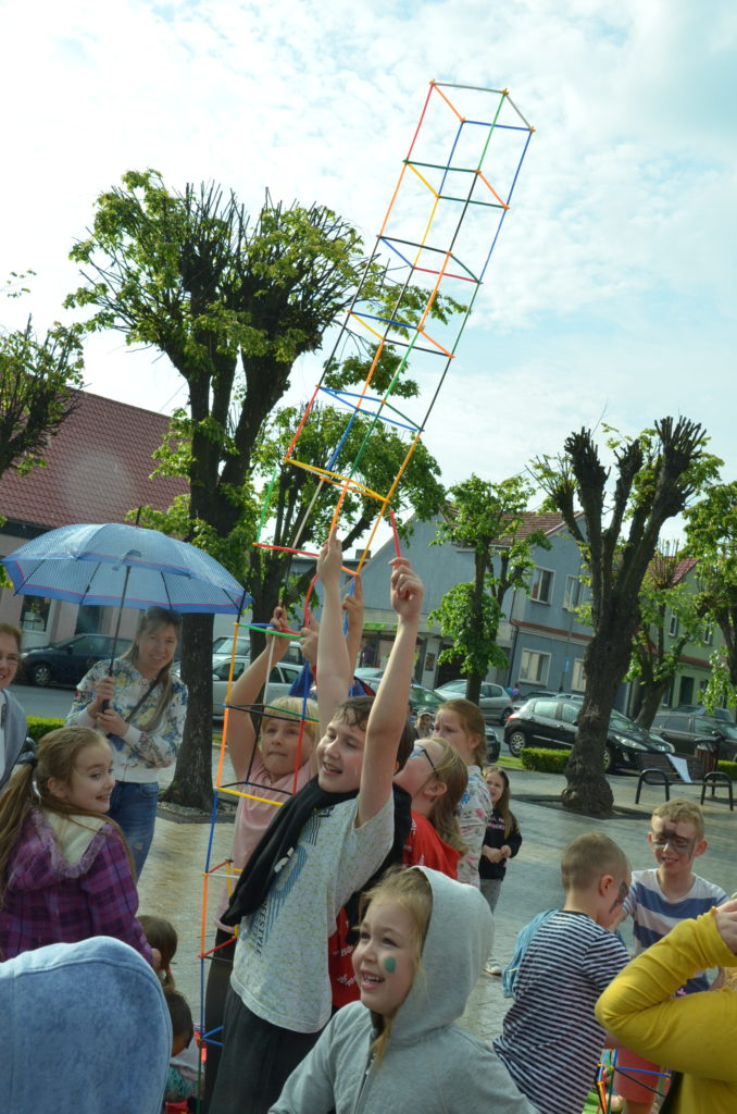 Na obrazku dzieci pokazują zbudowane przez siebie konstrukcje z klocków-słomek