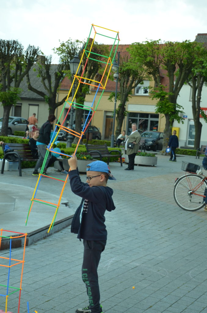 Na obrazku chłopiec trzyma wieżę zbudowaną z klocków-słomek