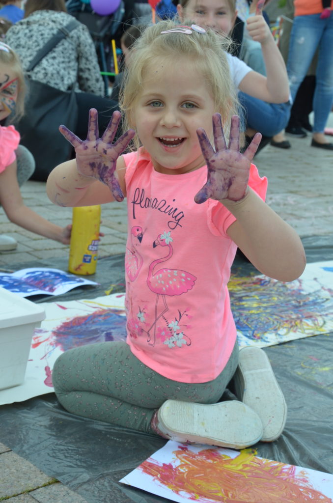 Na obrazku dziewczynka pokazuje kolorowe rączki