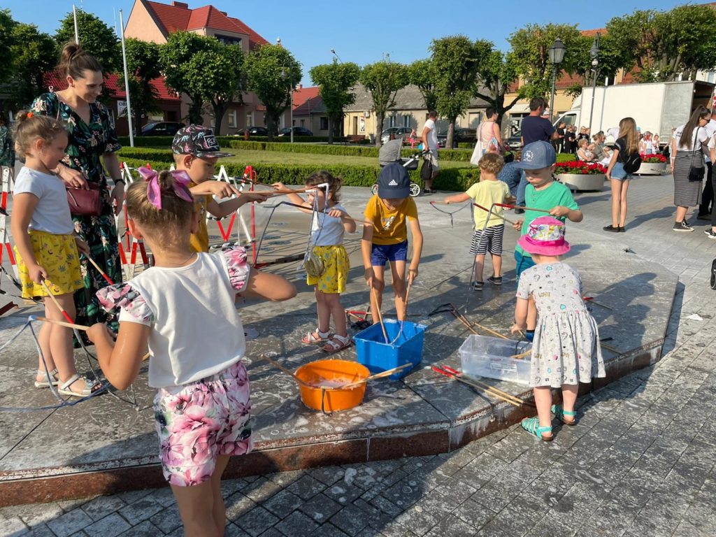 Na obrazku dzieci bawią się bańkami mydlanymi