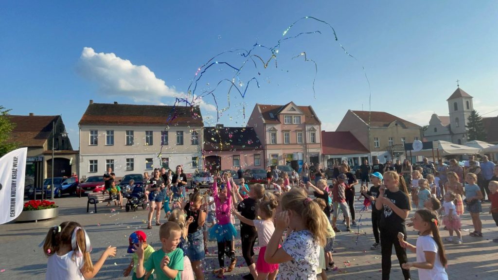 Na obrazku grupa dzieci bawi się bańkami mydlanymi