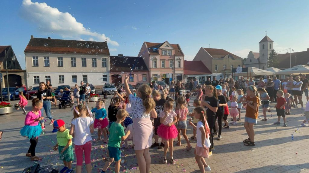 Na obrazku grupa dzieci bawi się bańkami mydlanymi