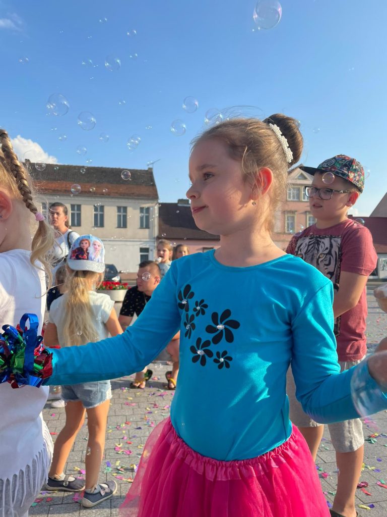 Na obrazku grupa dzieci bawi się bańkami mydlanymi