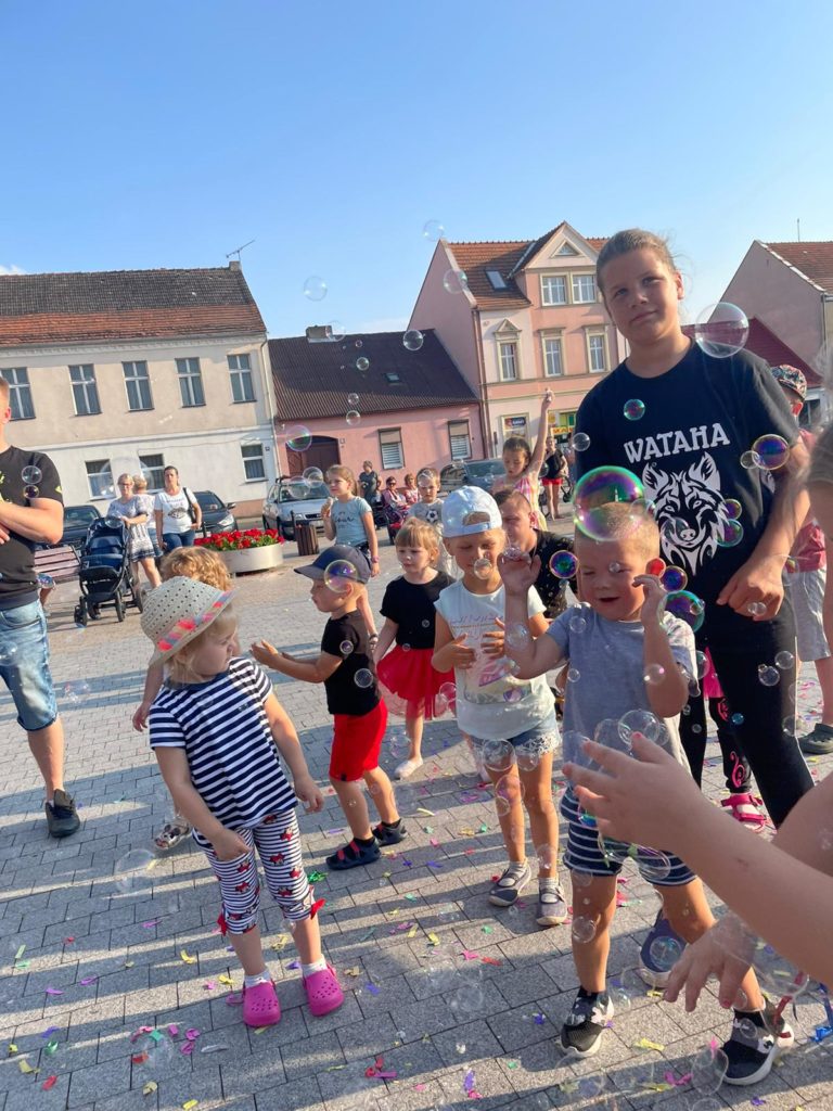 Na obrazku grupa dzieci bawi się bańkami mydlanymi