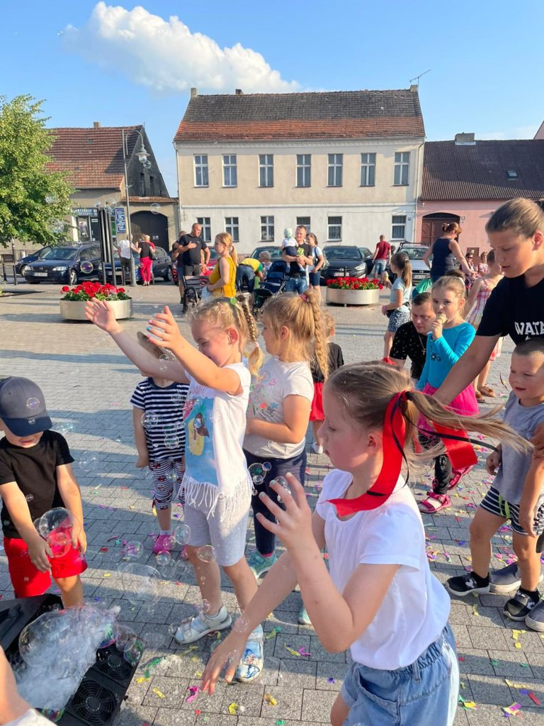 Na obrazku grupa dzieci bawi się bańkami mydlanymi