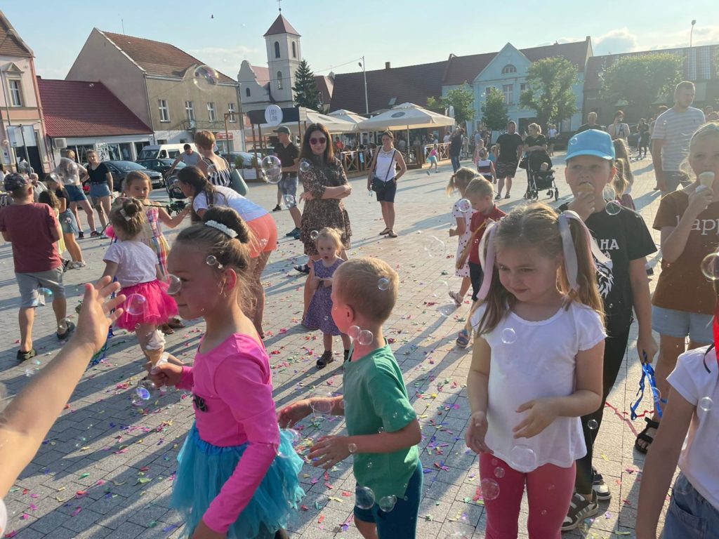 Na obrazku grupa dzieci bawi się bańkami mydlanymi