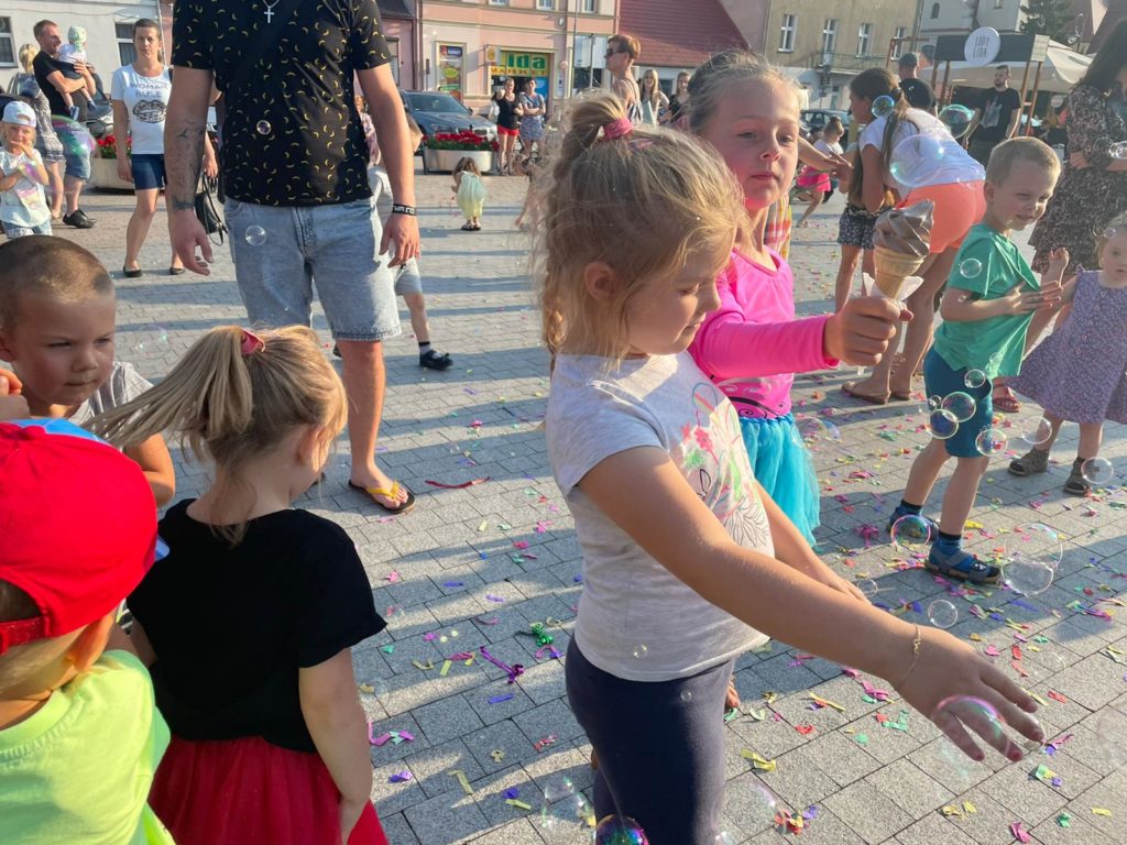 Na obrazku grupa dzieci bawi się bańkami mydlanymi