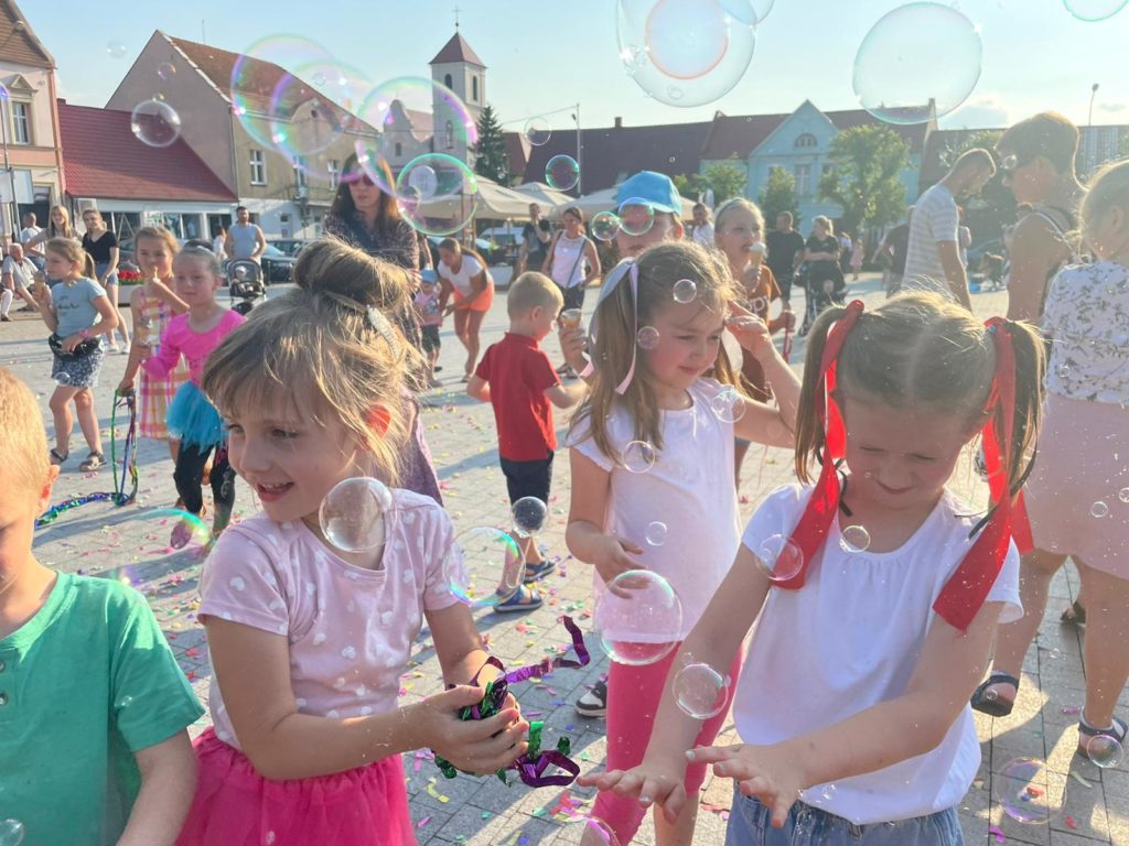Na obrazku grupa dzieci bawi się bańkami mydlanymi