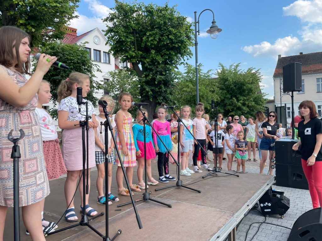 Na obrazku występuje grupa dzieci na scenie