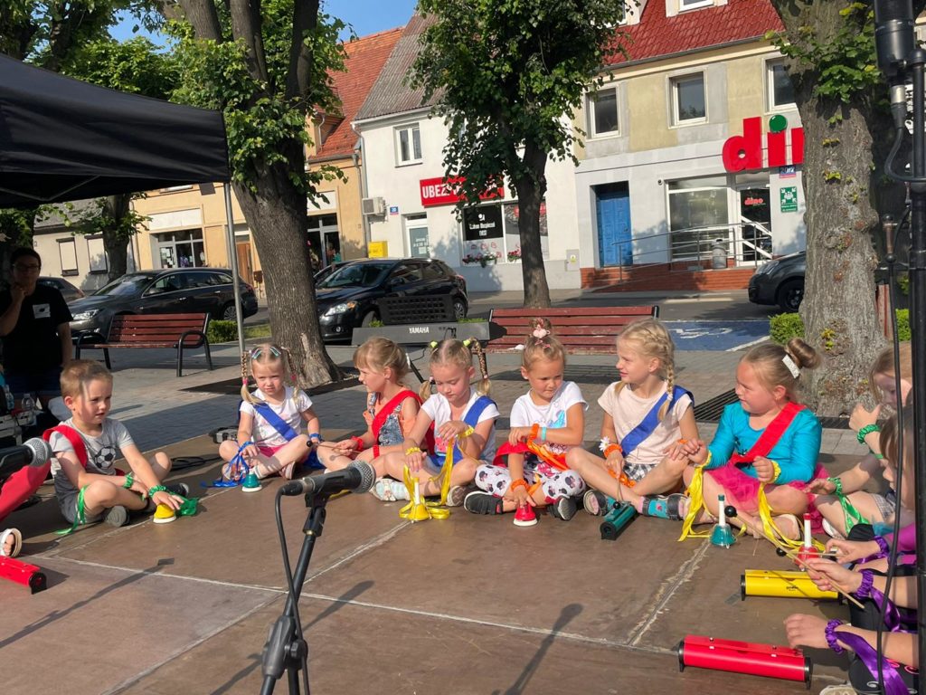 Na obrazku na scenie siedzi grupka dzieci
