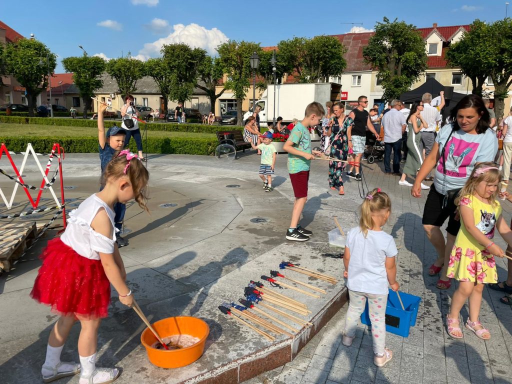 Na obrazku na rynku bawi się grupa dzieci