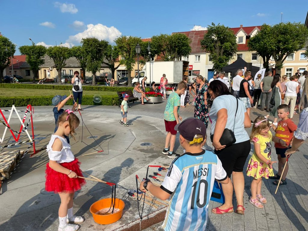 Na obrazku na rynku bawi się grupa dzieci