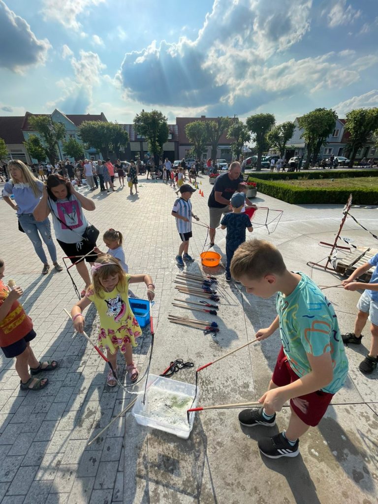 Na obrazku na rynku bawi się grupa dzieci