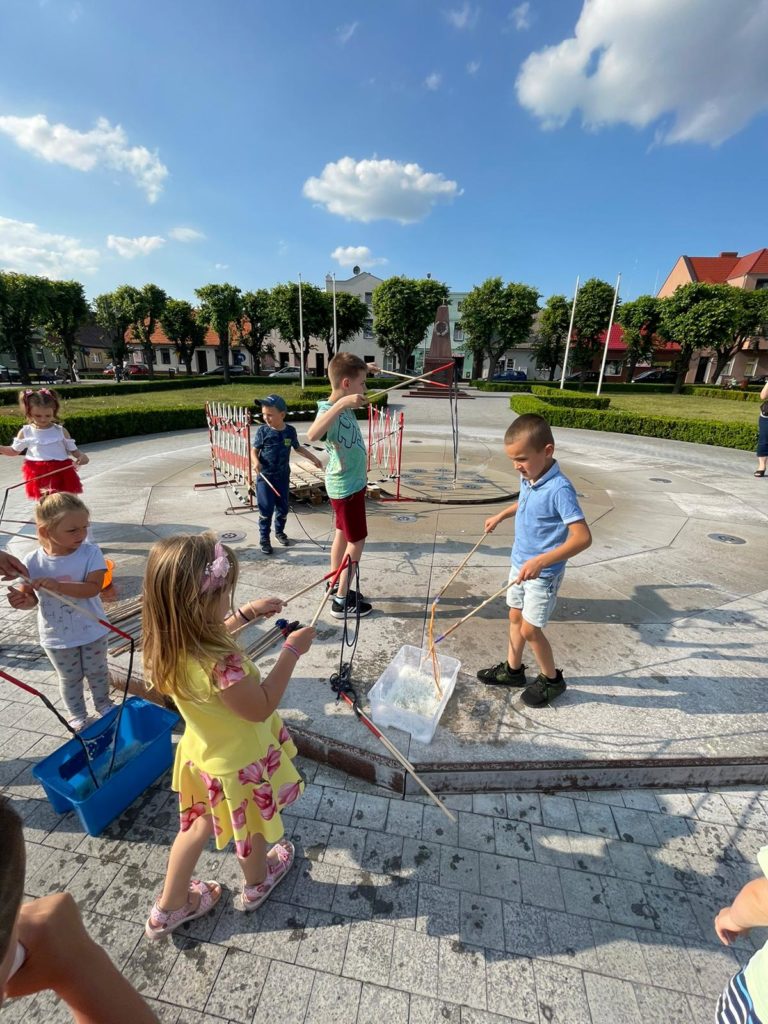 Na obrazku na rynku bawi się grupa dzieci