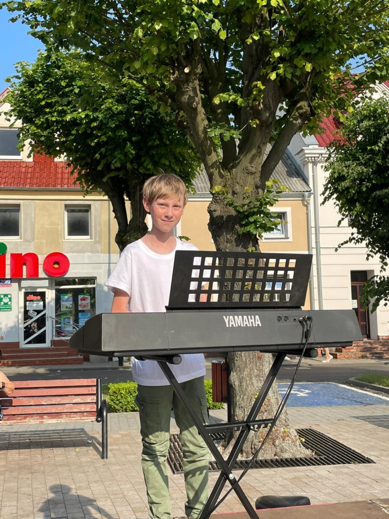Na obrazku jest chłopiec grający na keyboardzie