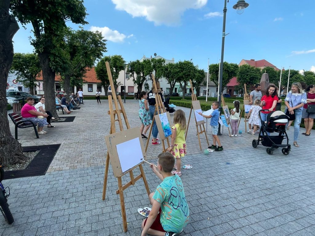 Na obrazku dzieci malują na sztaludze