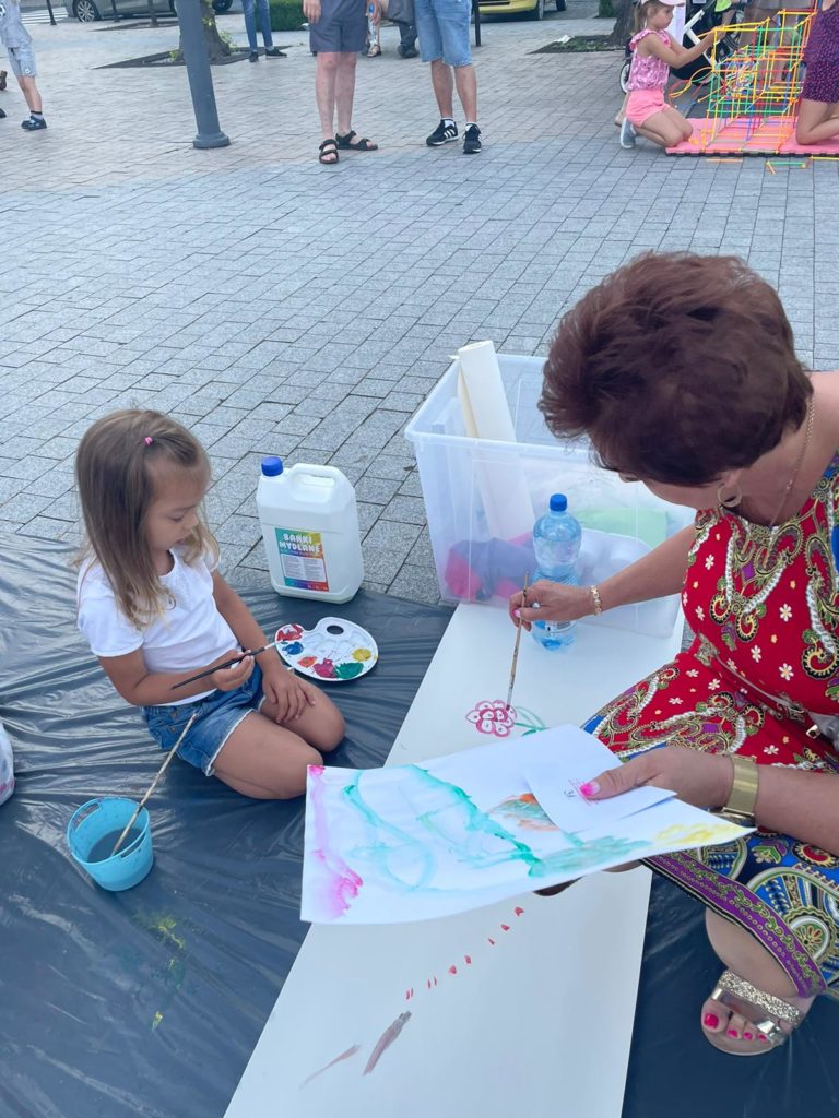 Na obrazku dziecko i kobieta malują na kartce papieru